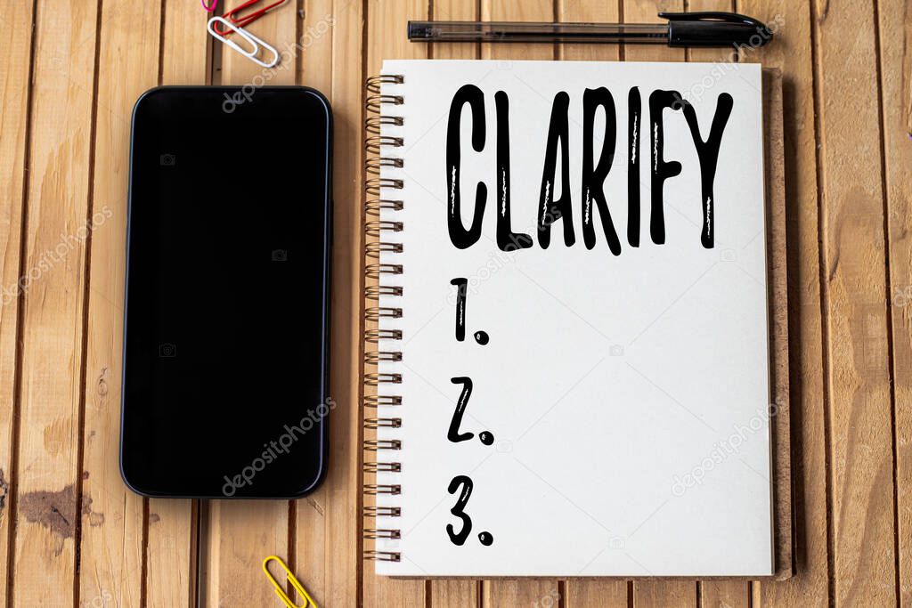 Text sign showing Clarify. Business approach Make a statement or situation less confused and more comprehensible Empty Open Journal Beside Mobile With Pens On Top Of Wooden Desk.