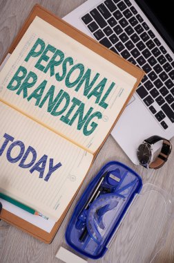 Kişisel Marka 'yı sunan metin başlığı. Ticari yaklaşım kendilerini ve markalar olarak kariyerlerini pazarlıyor. Pusula Kalem Kol Saati olan bir dizüstü bilgisayarın üzerinde Boş Not Defteri açıldı.