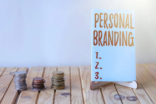 Texte d'inspiration Personal Branding. Idée d'entreprise Marketing eux-mêmes et leur carrière en tant que marques Pièce vide de papier sur support à côté de la pile de pièces sur le bureau. — Photo