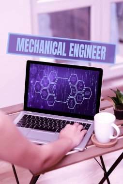 Metin Mekanik Mühendisi gösteriliyor. Mekanik Sistem Elleri için Uygulamalı Mühendislik Disiplini Bilgisayarda Kahve fincanı ve Fabrika 'nın yanında yazmakla meşgul.