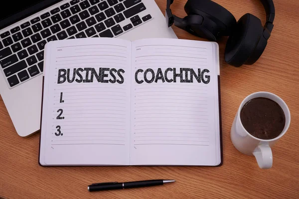 Bildunterschrift: Business Coaching. Internet-Konzept Mitarbeiter werden aktiver Beratung eines Experten Blanker Notizblock Laptop mit Stift und Kopfhörer neben einer Tasse warmen Kaffees. — Stockfoto