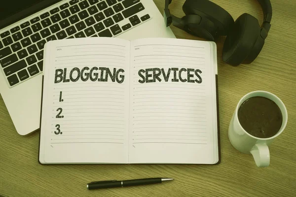 Znak tekstowy pokazujący Blogging Services. Koncepcja oznacza Social Networking obiektu Informacyjny Dziennikarstwo puste Notatnik Laptop z długopisem i słuchawki obok filiżanki ciepłej kawy. — Zdjęcie stockowe