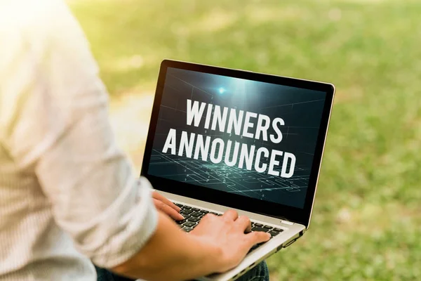 Text caption presenting Winners Announced. Word Written on Announcing who won the contest or any competition Woman Typing On Laptop Sitting Outside Back View Working From Home. — Stock Photo, Image