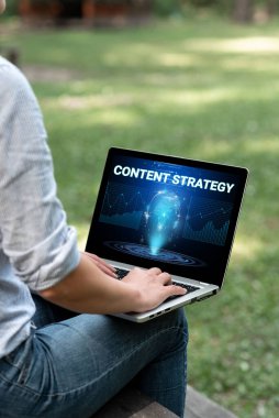 El yazısı içerik stratejisi. Kavramsal fotoğraf, iyi fotoğraflar ve sözcüklerle pazarlama planı oluşturur. Laptop 'ta yazan kadın dışarıda oturuyor. Evden çalışıyor..