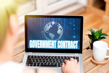 Hükümet Sözleşmesi 'ni sunan metin başlığı. Ev yapımı kahve fincanının ve fabrikanın yanındaki dizüstü bilgisayarda yazan Yönetici Kadına Hizmetleri satmak için Anlaşma Süreci Sözcüğü.