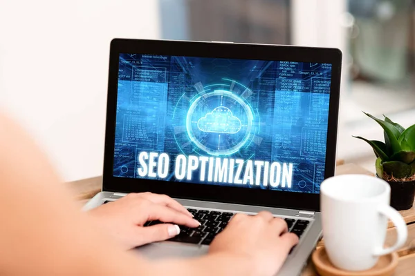 El yazısı tabelası Seo Optimizasyonu. İnternet sitesinin ya da sayfanın görünürlüğünü etkileyen kavramsal fotoğraf süreci ev bilgisayarından çalışan kahve fincanı ve bitkinin yanındaki dizüstü bilgisayarda el yazısı. — Stok fotoğraf