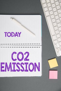 Metin Co2 Emisyonu gösteriliyor. İş yaklaşımı, sera gazı salınımını zaman içinde atmosfere salıyor. Not Defteri ve Yapışkan Notlu Kalemlerin Üzerinde Bir Masa Üzerinde Klavye