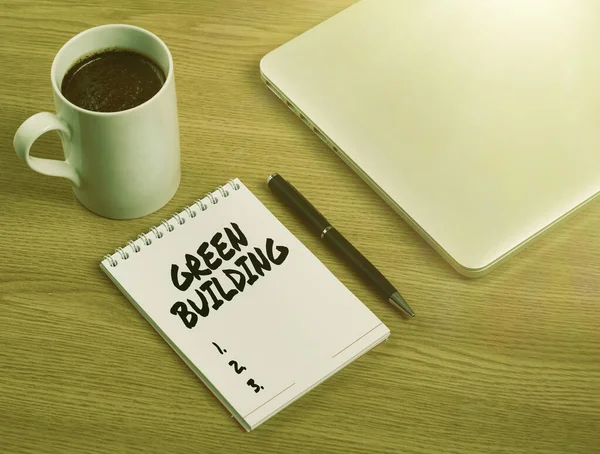 Conceptual caption Green Building. Business concept A structure that is environmentally responsible Sustainable Closed Laptop Beside Empty Journal With Pen And Coffee Mug Over Table. — Foto Stock