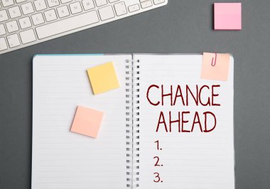 Metin işareti İleride Değişiklik Gösteriyor. İş fikri. Bazı değişiklikler gerçekleşmeyi bekliyor. Bir Not Defteri ve Yapışkan Notlu Kalemlerin Yanında Bir Masa Üzerinde Perspektif Klavye