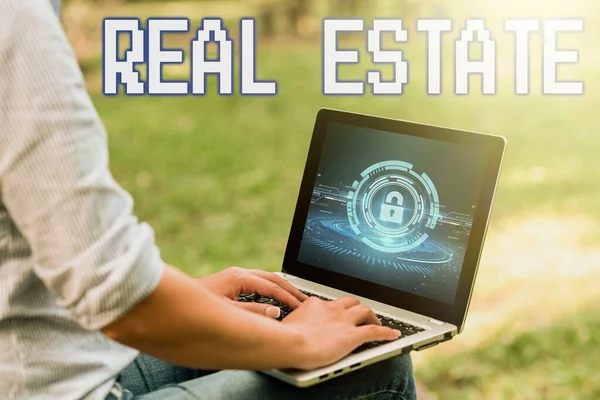 Writing displaying text Real Estate. Concept meaning total property consisting of both natural resource and building Woman Sitting With Latop Alone In The Park Accomplishing Remote Jobs.