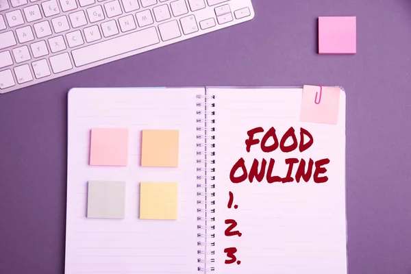 显示网上食物的文字标志。在一个由商店键盘直接提供的网站上，在一本笔记本旁边的桌子上和贴有薄纸的钢笔上，建立了各种各样的商业概念 — 图库照片