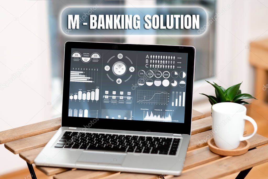 Handwriting text M banking Solution. Concept meaning conduct financial transaction remotely by mobile device Laptop Resting On A Table Beside Coffee Mug And Plant Showing Work Process.