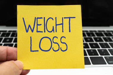 Kavramsal manşet Kilo Verme. Çalışma için klavye, klavye ve kahve fincanı ile masadaki sıvı ofis malzemelerinin kaybından dolayı toplam vücut kütlesinin azaltılması fikri