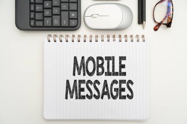 Kavramsal başlık Mobil Mesajlar. İş konsepti elektronik mesajlar yazma ve gönderme ofis malzemeleri üzerinde klavye, bardak ve çalışma için kahve fincanı ile