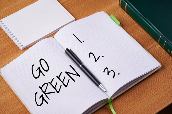 Texto que muestra inspiración Go Green. Idea de negocio toma de decisiones más respetuosas con el medio ambiente como reducir el reciclaje liso Cuadernos abiertos en blanco con pila de plumas contenedor sobre la mesa. — Foto de Stock