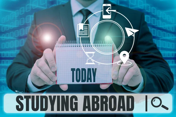 Podepsat zobrazení Studium v zahraničí. Koncept znamená učit se mimo domov v cizí zemi Cestování Podnikatel v obleku drží notepad symbolizující úspěšnou týmovou práci. — Stock fotografie