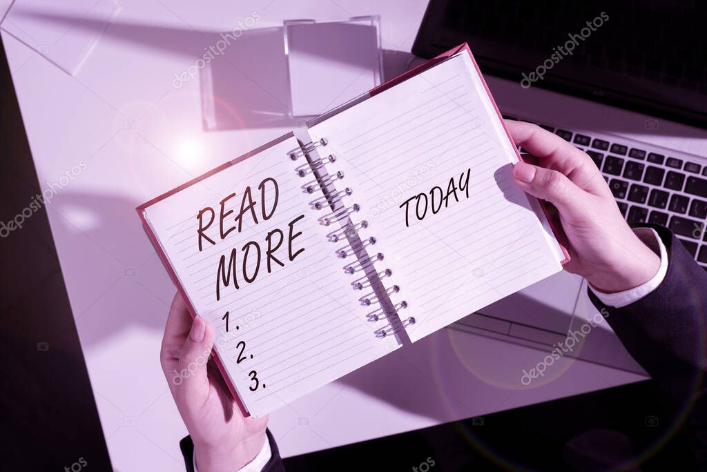 Conceptual caption Read More, Business concept Provide more time or thorough reading for a specific topic or item Blank Open Spiral Notebook With A Calculator And A Pen On Table.