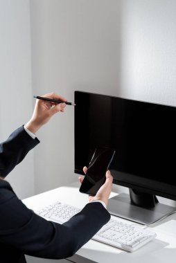 İş kadını cep telefonuyla önemli mesajlar masasında oturuyor..