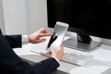 İş kadını cep telefonuyla önemli mesajlar masasında oturuyor..