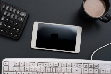 Masasında yeni bir mesaj olan cep telefonu, klavye, hesap makinesi ve kahve..