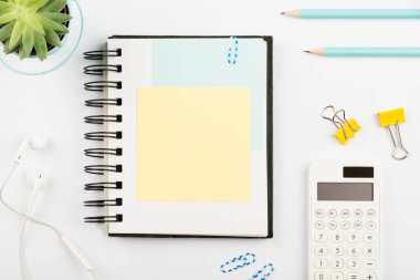 Masasında kalemler, kulaklıklar ve çiçekli yeni mesajlar olan defter..