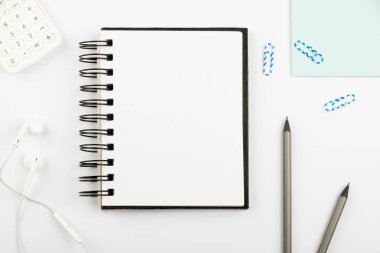 Masasında kalemler, kulaklıklar ve ataçlarla yeni bir mesaj olan defter..