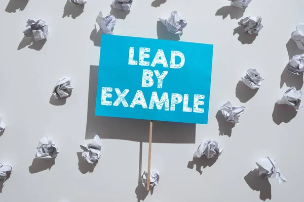 Writing displaying text Lead By Example, Word Written on Be a mentor leader follow the rules give examples Coach Wrinkled Notes Under Piece Of Paper With Important Message Glued On Stick.