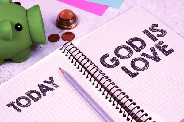 Sign displaying God Is Love, Concept meaning Believing in Jesus having faith religious thoughts Christianity Important Message On Notebook On Desk With Money, Pen, Notes And Pig Box.