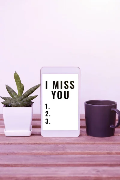 Writing displaying text I Miss You, Conceptual photo Feeling sad because you are not here anymore loving message Tablet With Important Information On Table With Plant And Cup Of Coffee.
