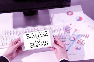Hand writing sign Beware Of Scams, Business approach Stay alert to avoid fraud caution be always safe security Woman Holding Notebook With New Ideas Over Desk With Computer And Keyboard.