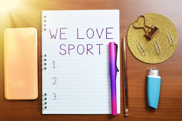 Text showing inspiration We Love Sport, Word Written on To like a lot practicing sports athletic activities work out Notebook With Important Message On Desk With Office Supplies.