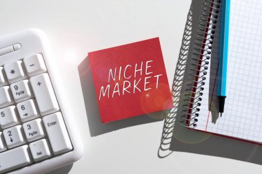 Hand writing sign Niche Market, Word Written on Subset of the market on which specific product is focused Important Messages Written On Note On Desk With Pen, Notebook And Keyboard.