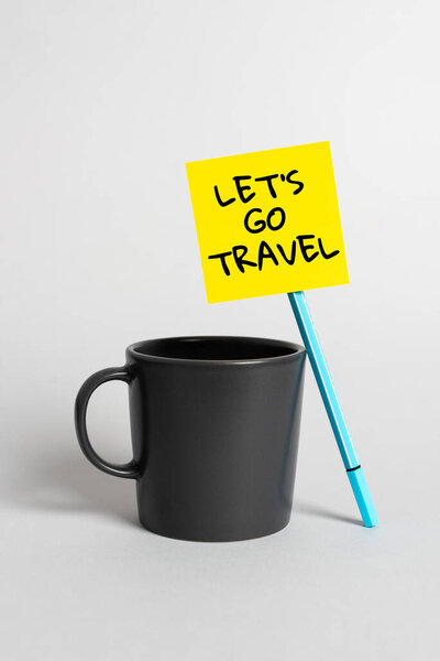 Inspiration showing sign Let S Is Go Travel, Conceptual photo Plan a trip visit new places countries cities adventure Cup, Pen And Sticky Note With Important Announcement On Desk.