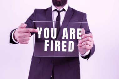 Sign displaying You Are Fired, Business idea Getting out from the job and become jobless not end the career Businessman Holding Transparent Glass And Promoting The Company Brand.