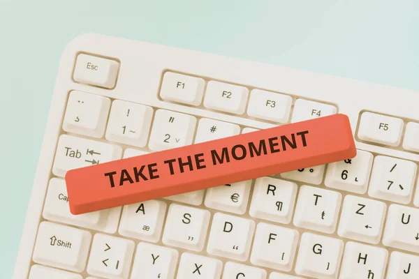 Text caption presenting Take The Moment, Word for Seize the day and opportunity be happy optimistic positive Woman Holding Pen On Desk With Lap Top, Books And Note With Important Data.