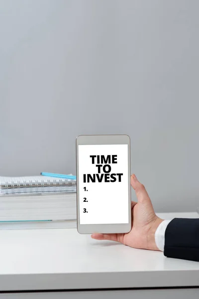 Text caption presenting Time To Invest, Word Written on Creation of capital capable of producing other goods Hands Of Woman With Blank Paper, Coffee Cup And Stationery Over Wood.