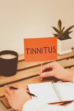 Tinnitus 'u, iş görüşünü, çalan müziği ve kulaklarda benzer bir ses duyusunu gösteren metin işareti.