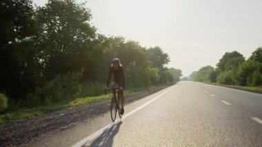 Kasklı erkek bisikletçi boş bir pistte bisiklet sürüyor.