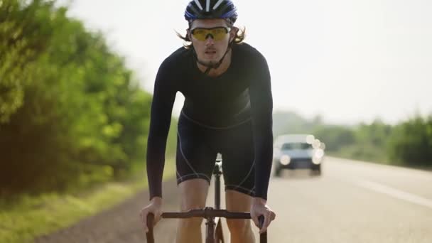 Мужчина-велосипедист в шлеме едет на велосипеде по трассе, набирая скорость — стоковое видео