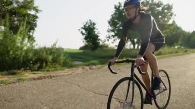 Genç bisikletçi bozuk aspalt yolda kusurlu bisiklet sürüyor.