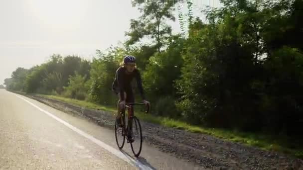 Ciclista masculino no capacete anda de bicicleta ao longo de uma pista vazia, câmera lenta — Vídeo de Stock