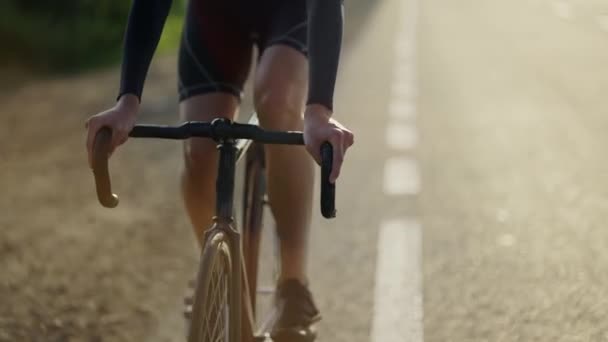 Cropped front view of a male cyclist rides bicycle along track in the morning, slow motion — Stock Video