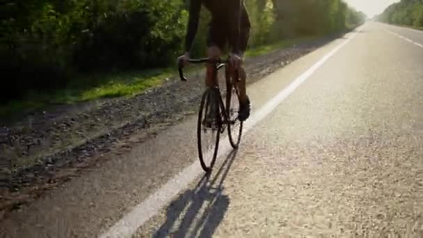 Vista ritagliata di un ciclista di sesso maschile in bicicletta lungo una pista vuota — Video Stock