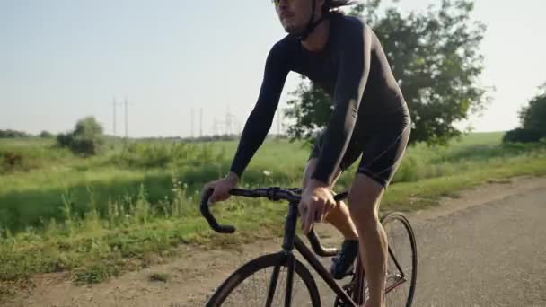 Спортсмен їде на велосипеді по асфальтовій дорозі сам — стокове відео