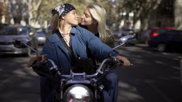 Portret van twee millenial meisjes zoenen terwijl stoppen op het stoplicht op motobike — Stockvideo