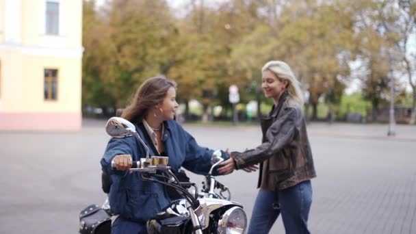 Dwie piękne młode kobiety siedzące na motocyklu na ulicy miasta i uśmiechnięte — Wideo stockowe