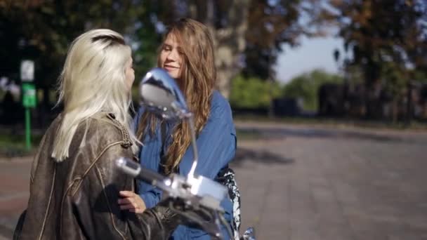 Två unga kvinnor kysser monterade på motorcykeln i staden — Stockvideo