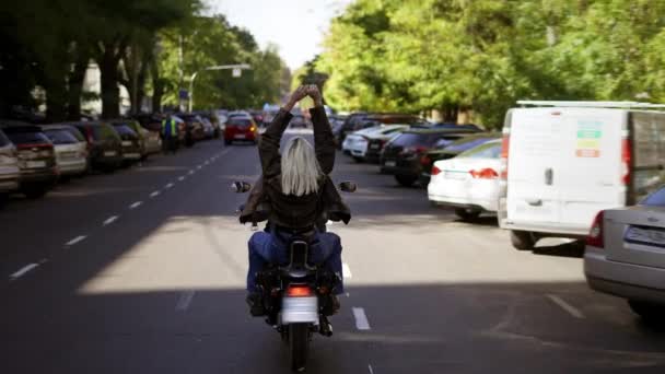 街の通りでバイクに乗って楽しむブロンドの女性の乗客,リアビュー — ストック動画