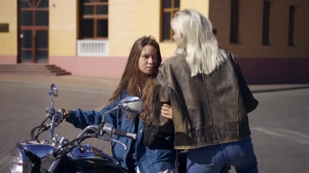 Портрет двох лесбійок закоханих сидять на мотоциклі, обіймаючи і погладжуючи один одного — стокове відео