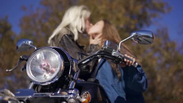 Дві тисячолітні дівчата чуттєво цілуються на змонтованому велосипеді - низький кут зору — стокове відео
